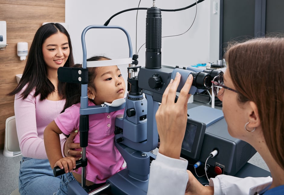 Optometrist performing a slit-lamp eye exam on a child with myopia.