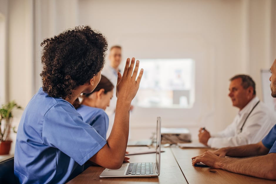 Eye care staff attending a team meeting, with one team member raising a hand.