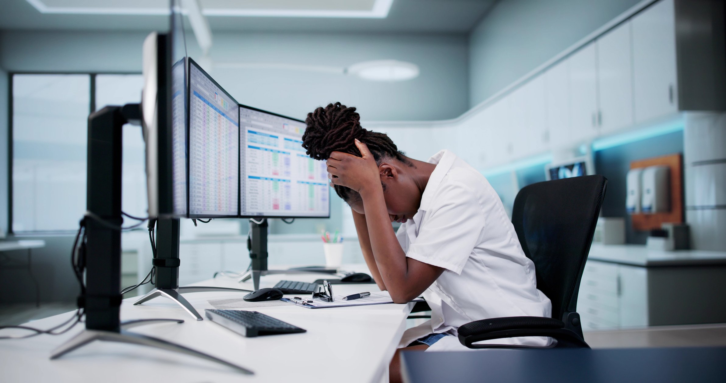 Ophthalmology billing staff feeling overwhelmed while reviewing data across multiple computer screens.