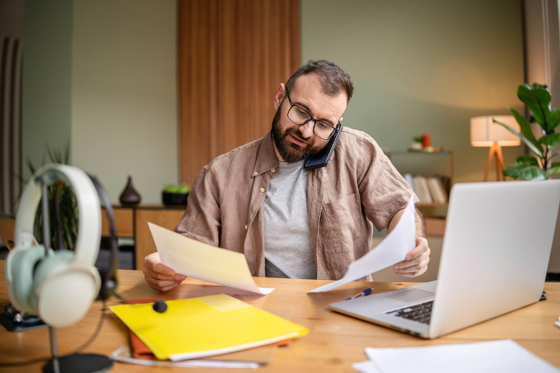 Busy patient juggling paperwork, laptop, and phone at work