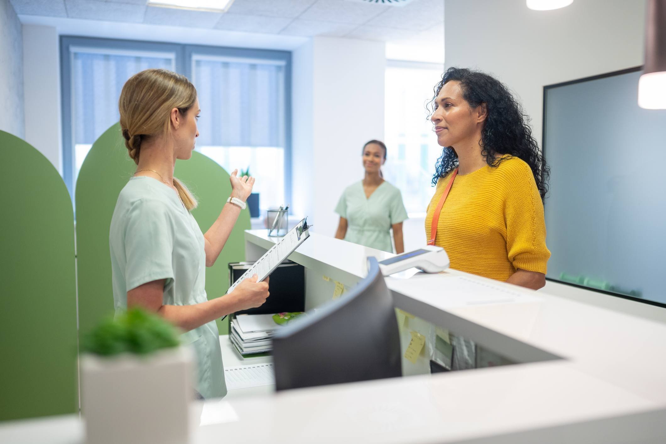 Front desk optometry staff communicating with smiling patient at the front desk, indicating positive patient engagement.