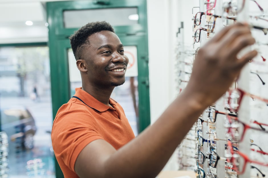 Male patient browsing and selecting eyeglass frames in an optical shop.