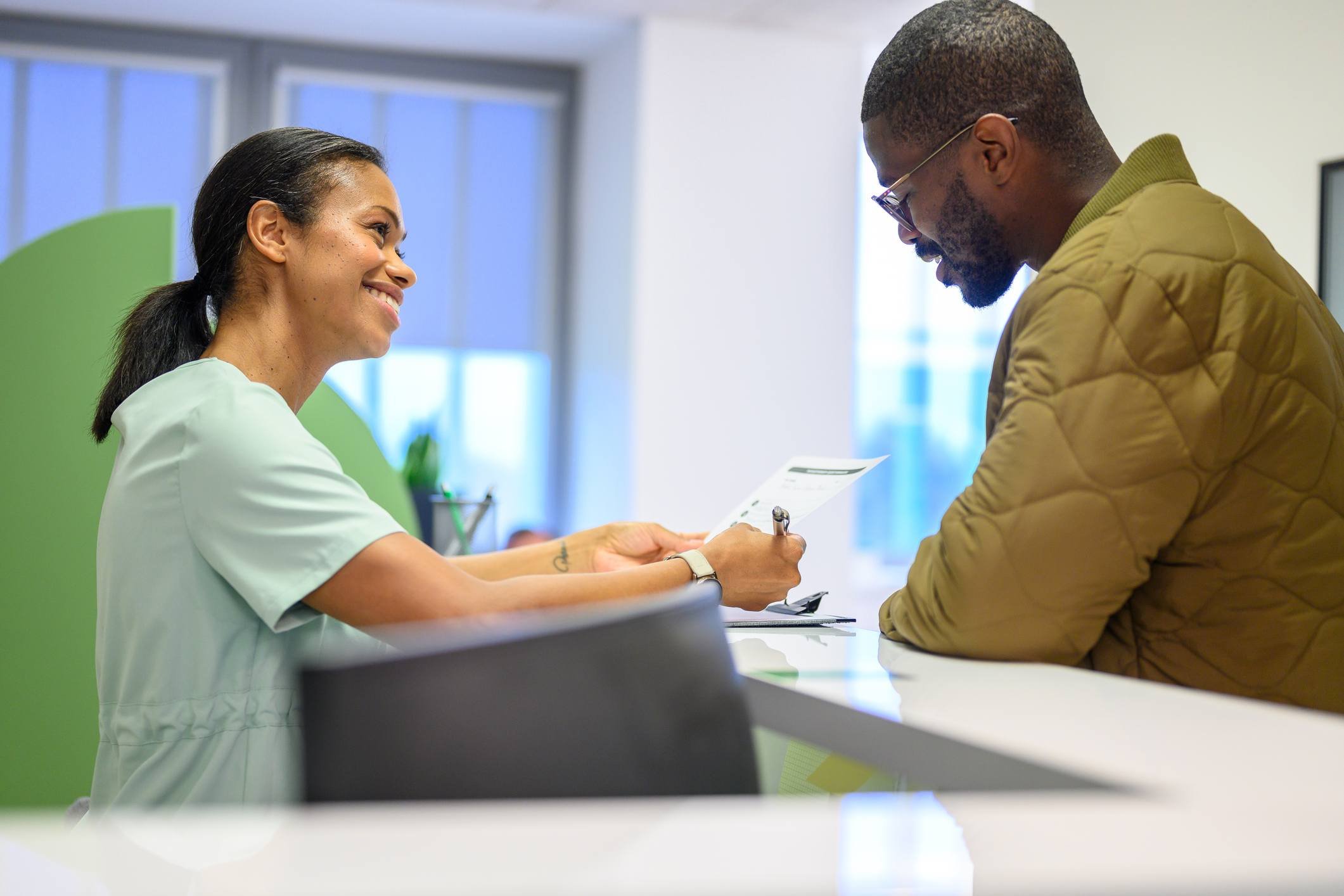 Front desk staff assisting patient with paperwork in ophthalmology practice