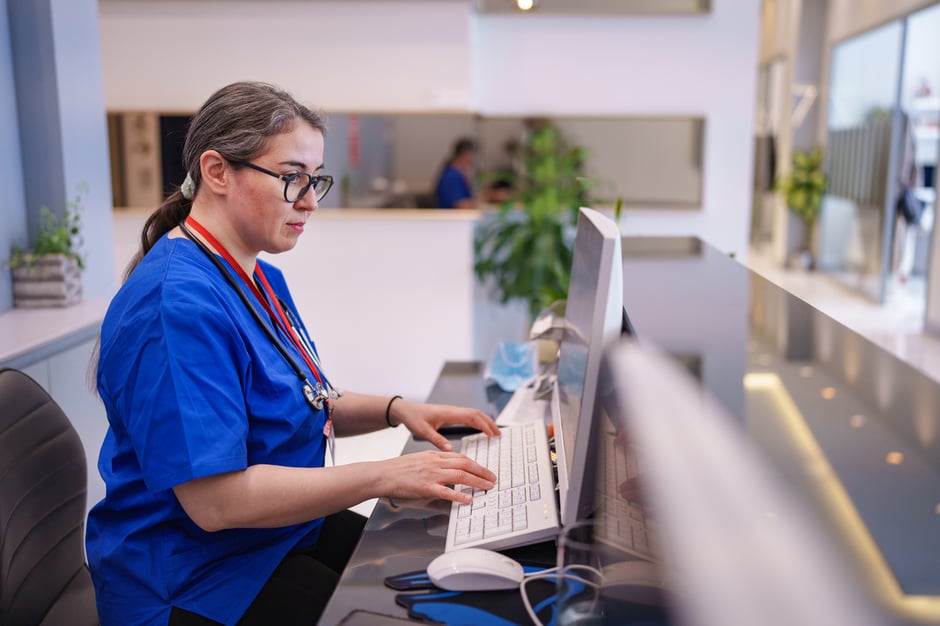 Administrative staff using an integrated EHR and ASC module on a computer.