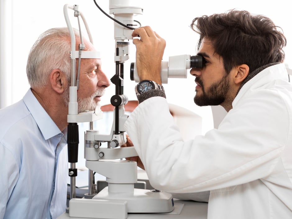 Ophthalmologist conducting eye exam on an elderly male patient.