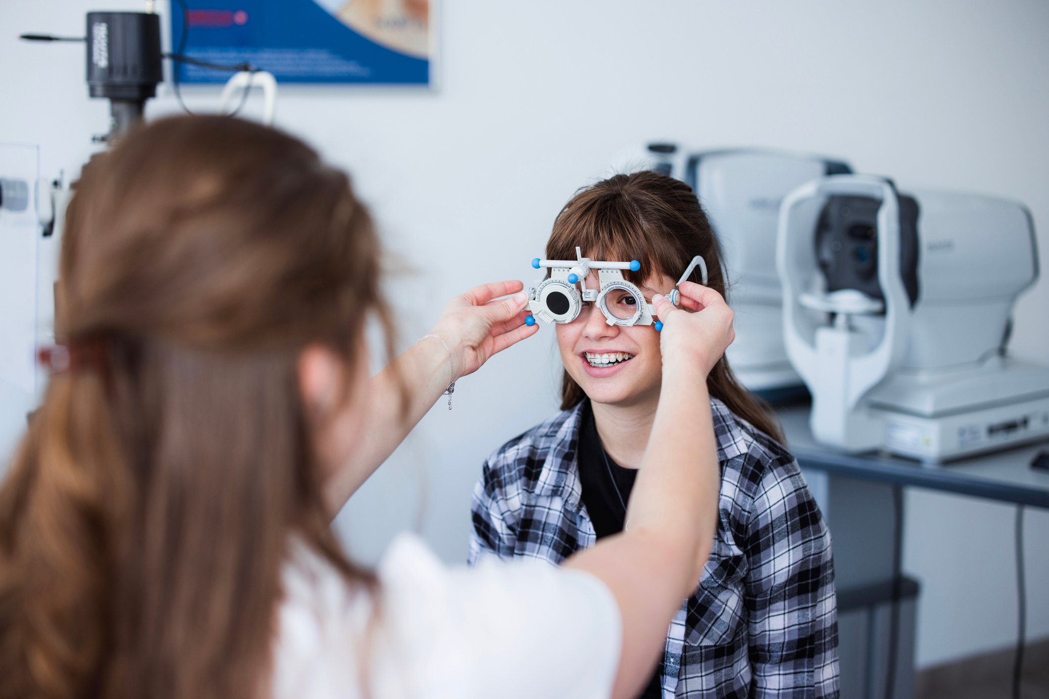 Eye care provider fitting trial lenses during a vision exam for a pediatric patient