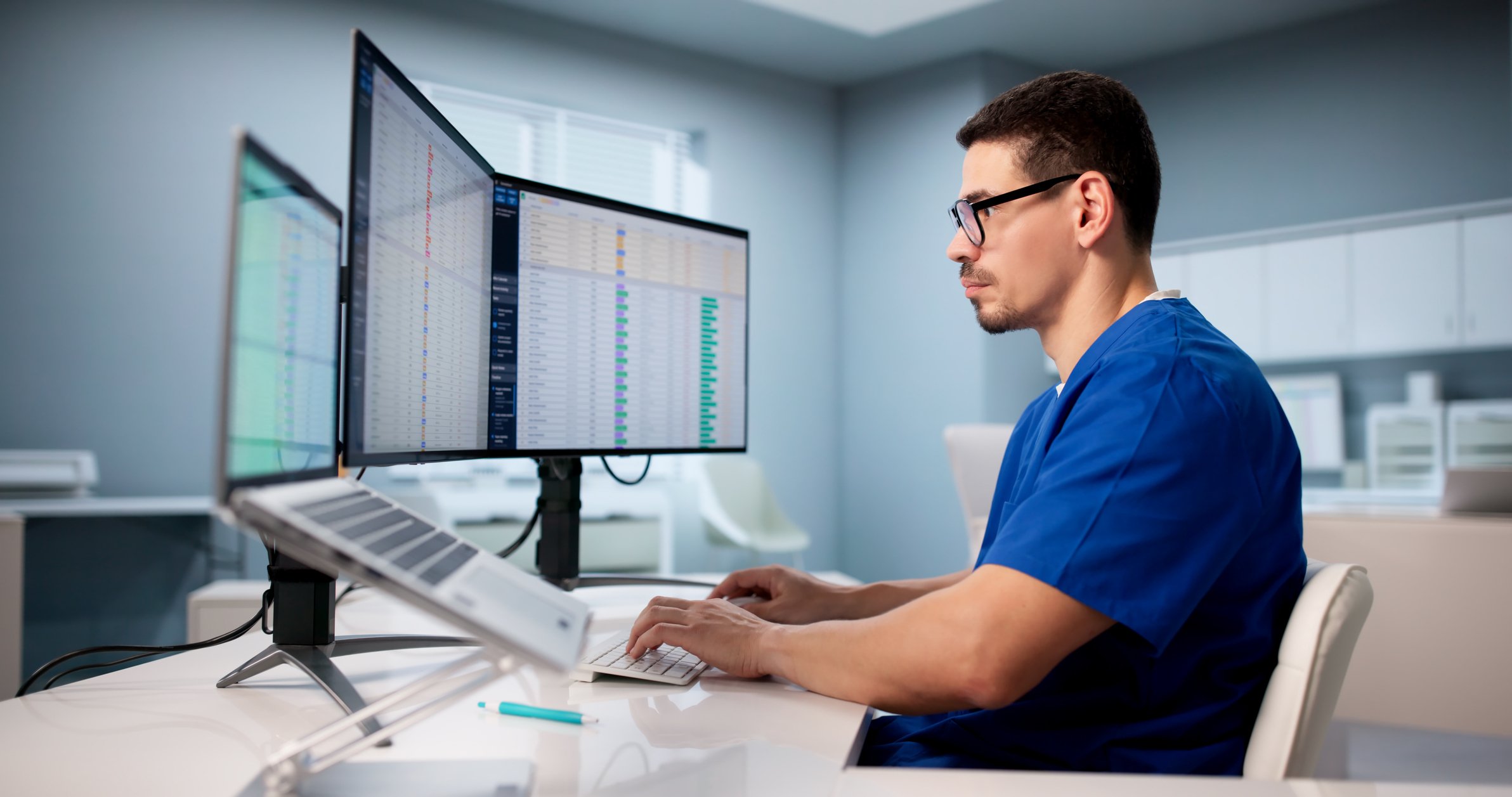 Ophthalmology staff reviewing billing data on dual monitors in a clinical office