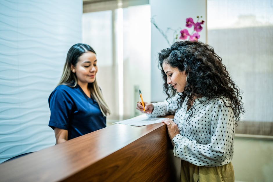 Patient happily checking in at the front desk of an ophthalmology practice.