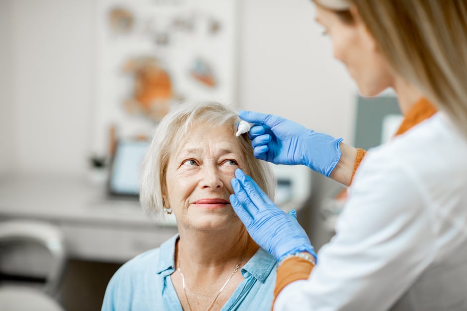Ophthalmology provider administering eye drops to an older patient, demonstrating a calm and reassuring patient experience.