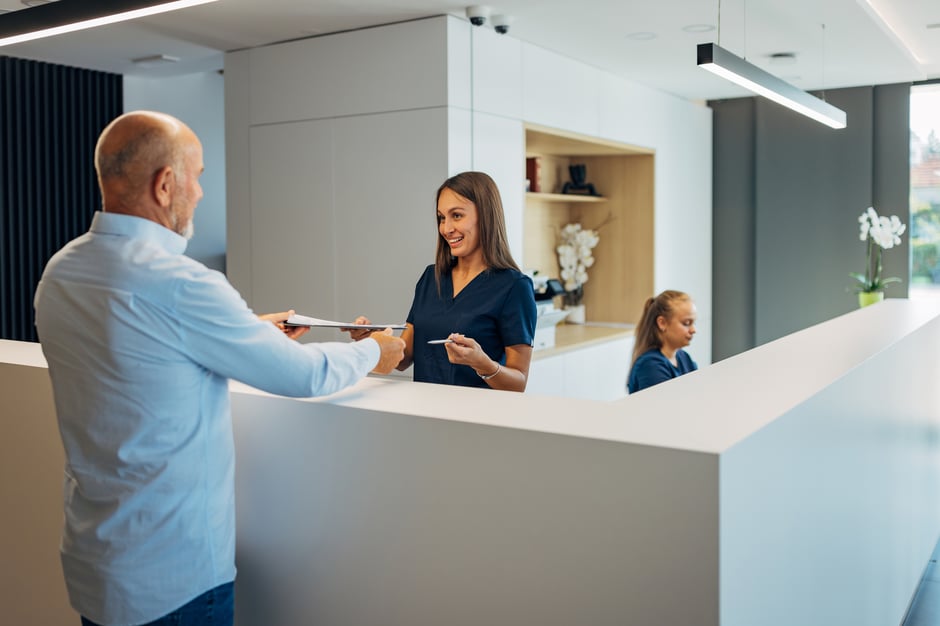 Eye care staff checking a patient checking in at a front desk using a modern optometry EHR