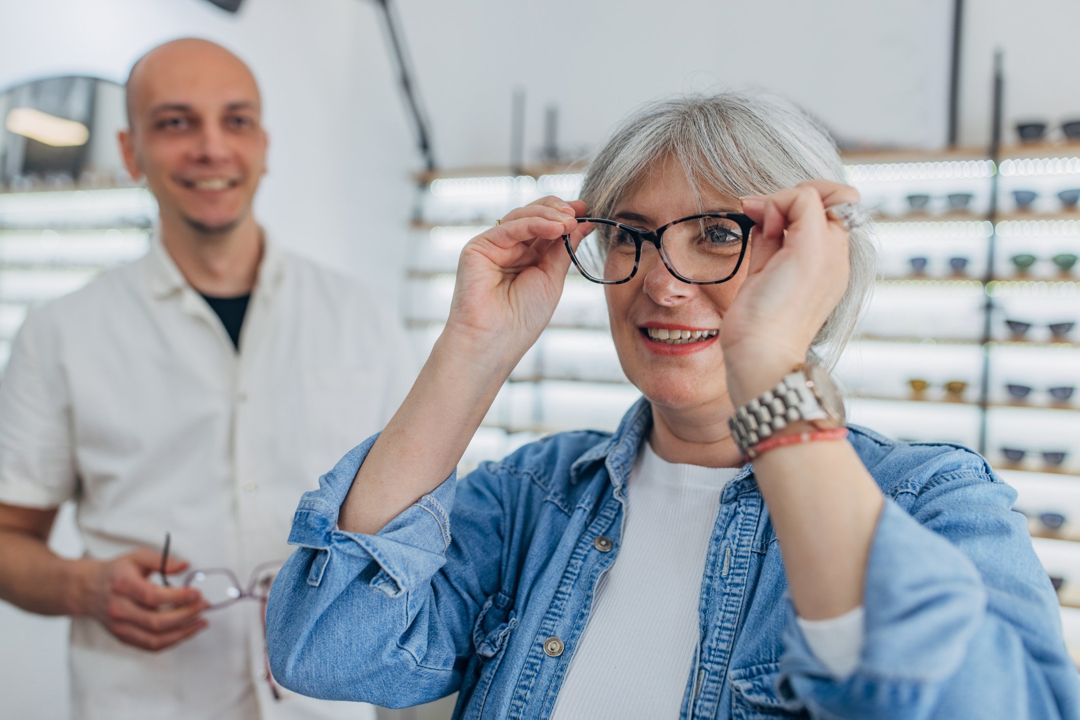 Female patient trying on a pair of glasses in the optical shop of an optometry clinic.