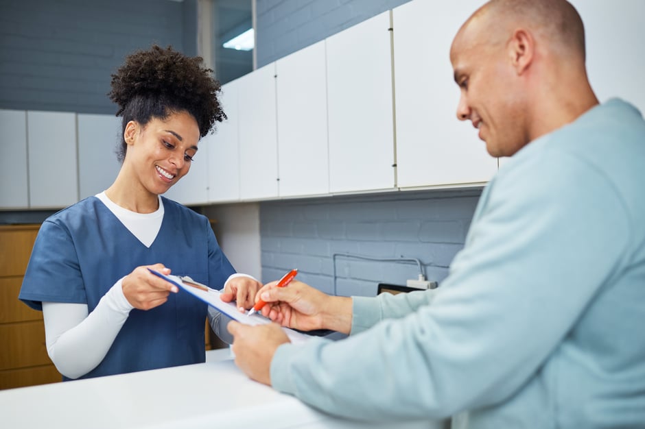 Front desk staff member assisting a patient with paperwork in an ophthalmology clinic.