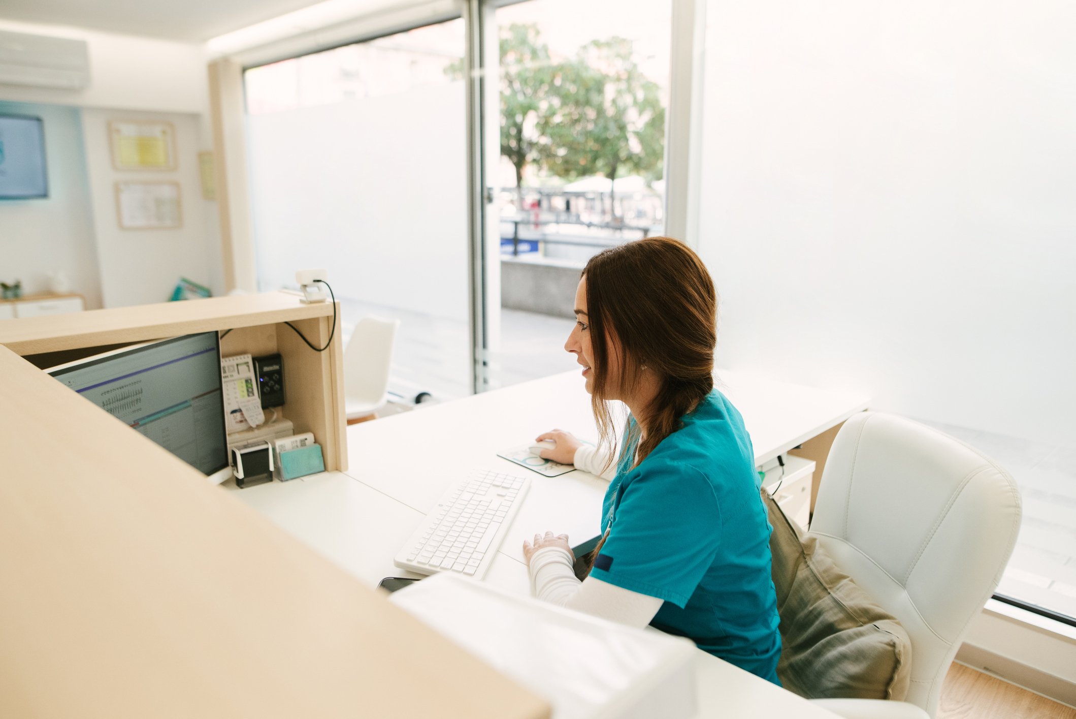 Optometry practice staff member working at front desk managing patient scheduling and check-in.