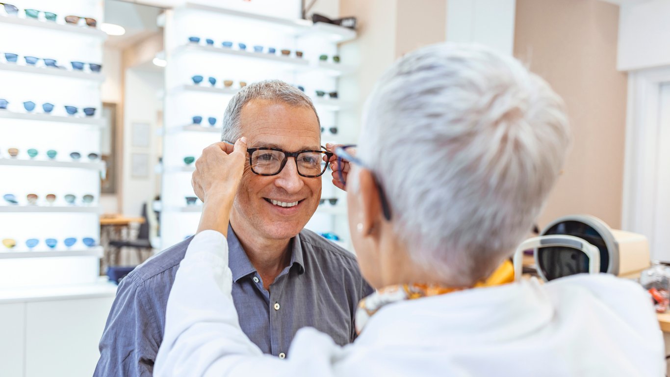 Optician assisting a patient with selecting eyeglass frames in an optometry clinic.