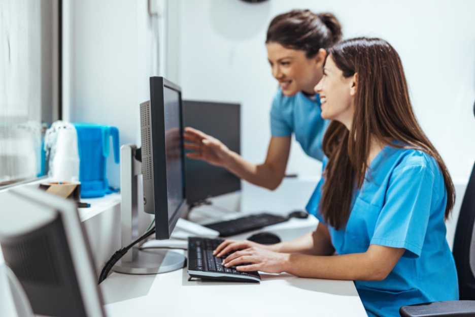 Two eye care staff members reviewing MIPS performance data in an ophthalmology EHR.